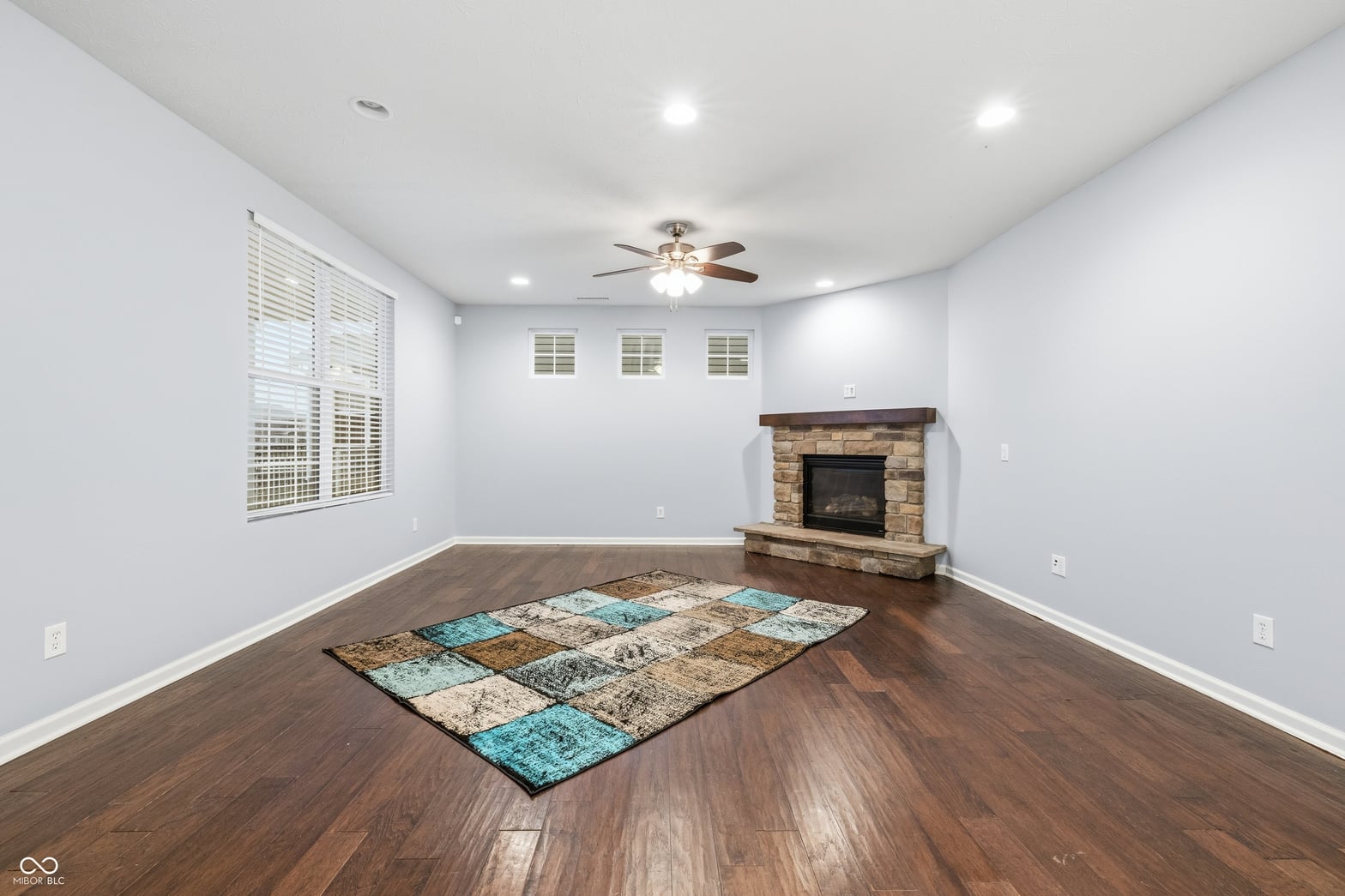 Spacious family room with stone fireplace and hardwoods.