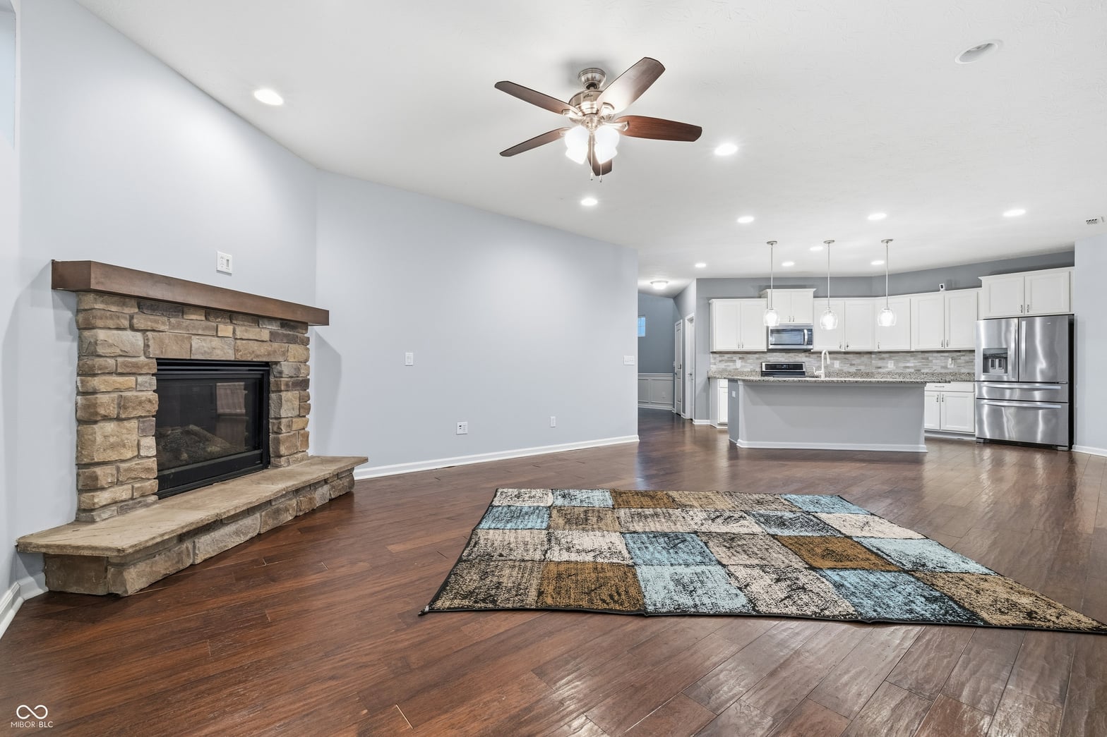 Open-concept living with stunning stone fireplace and modern kitchen.