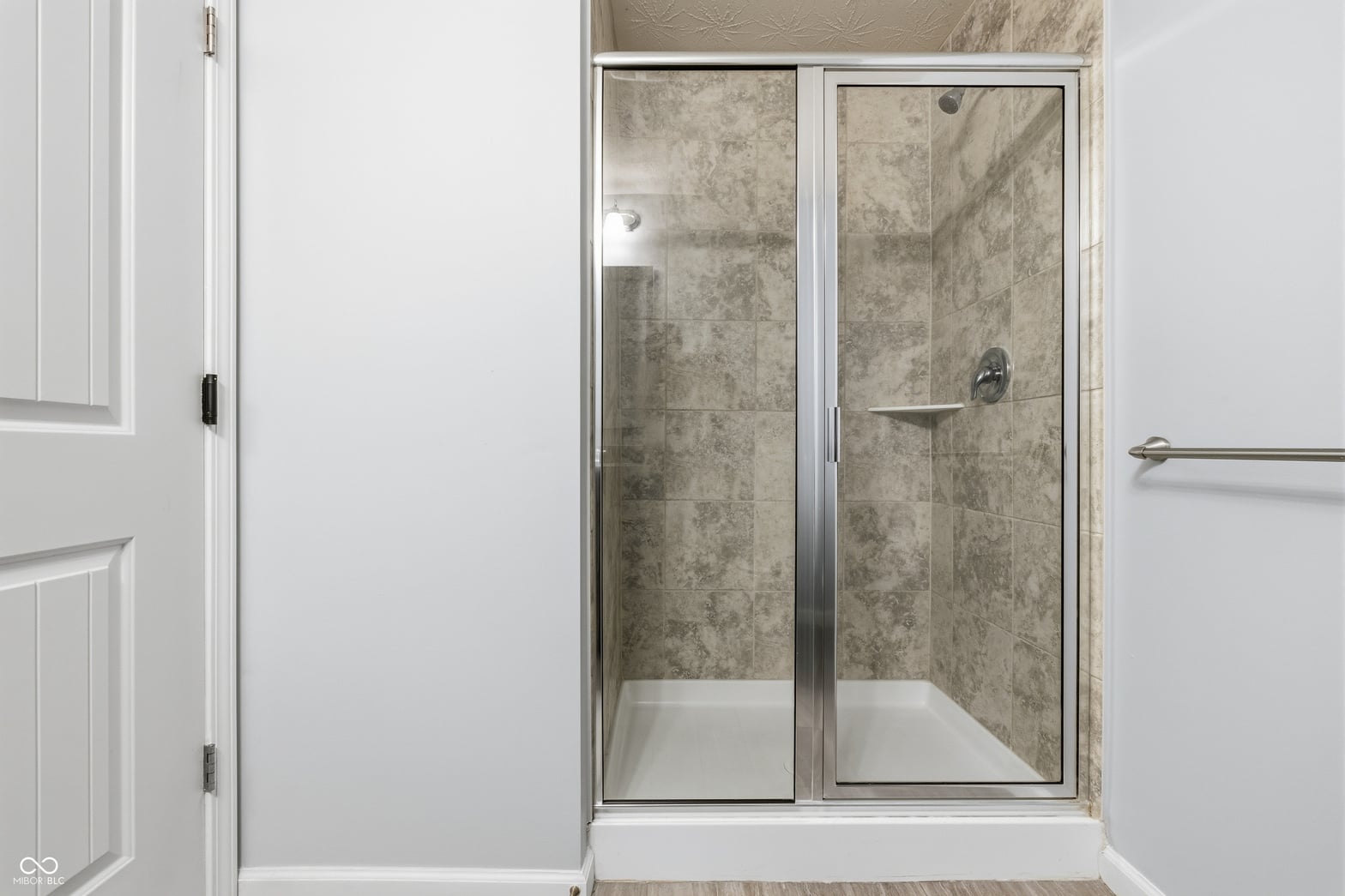 Modern frameless glass shower with elegant marble tile.