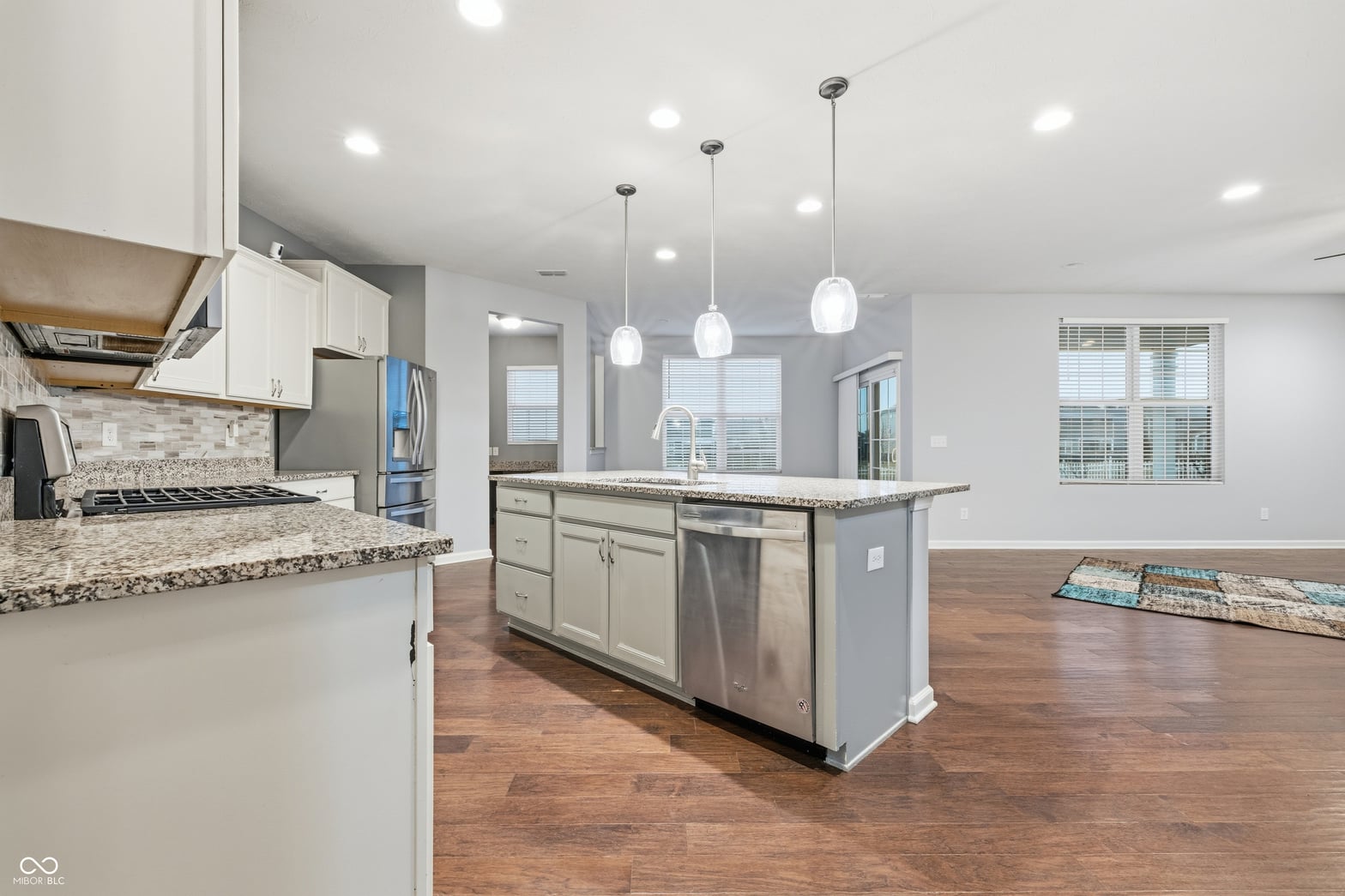 Bright modern kitchen with granite island and stainless steel.