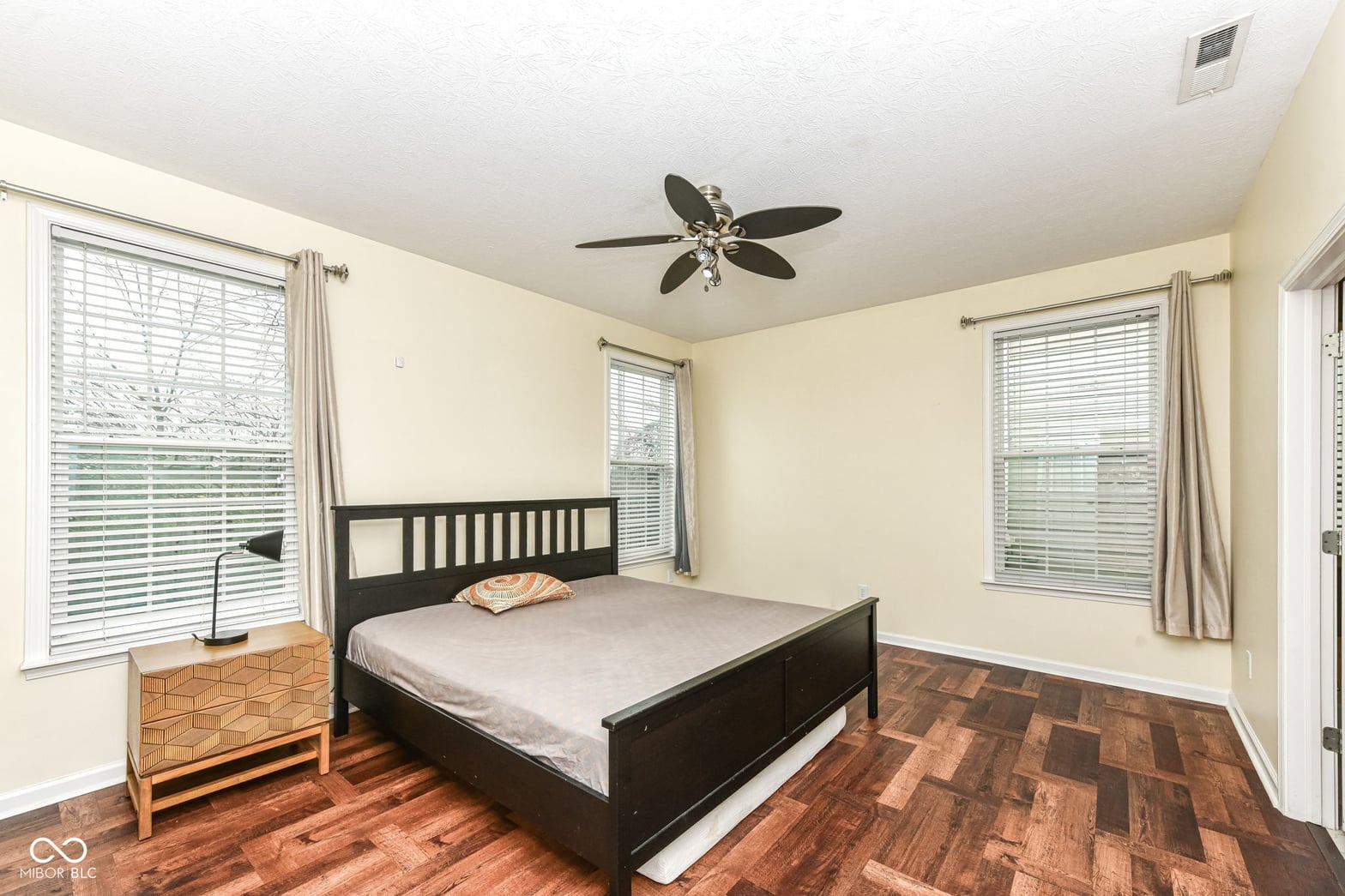 Bright primary bedroom with hardwood floors and abundant natural light.