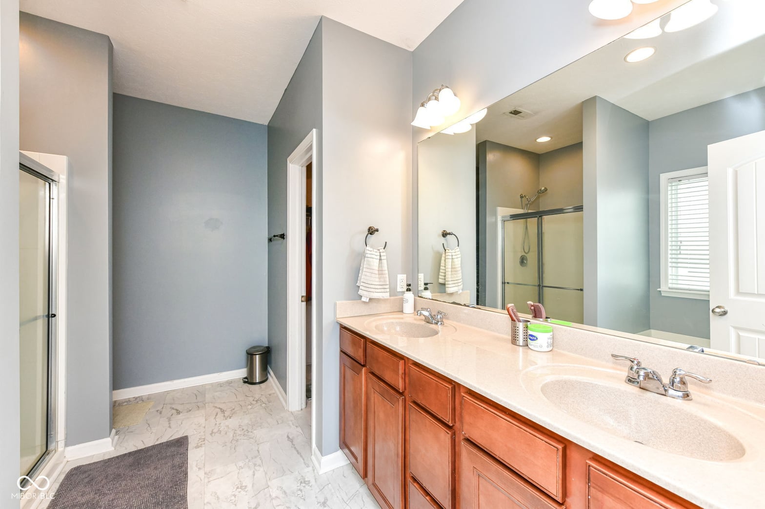 Spacious primary bath with double vanity and marble floors.