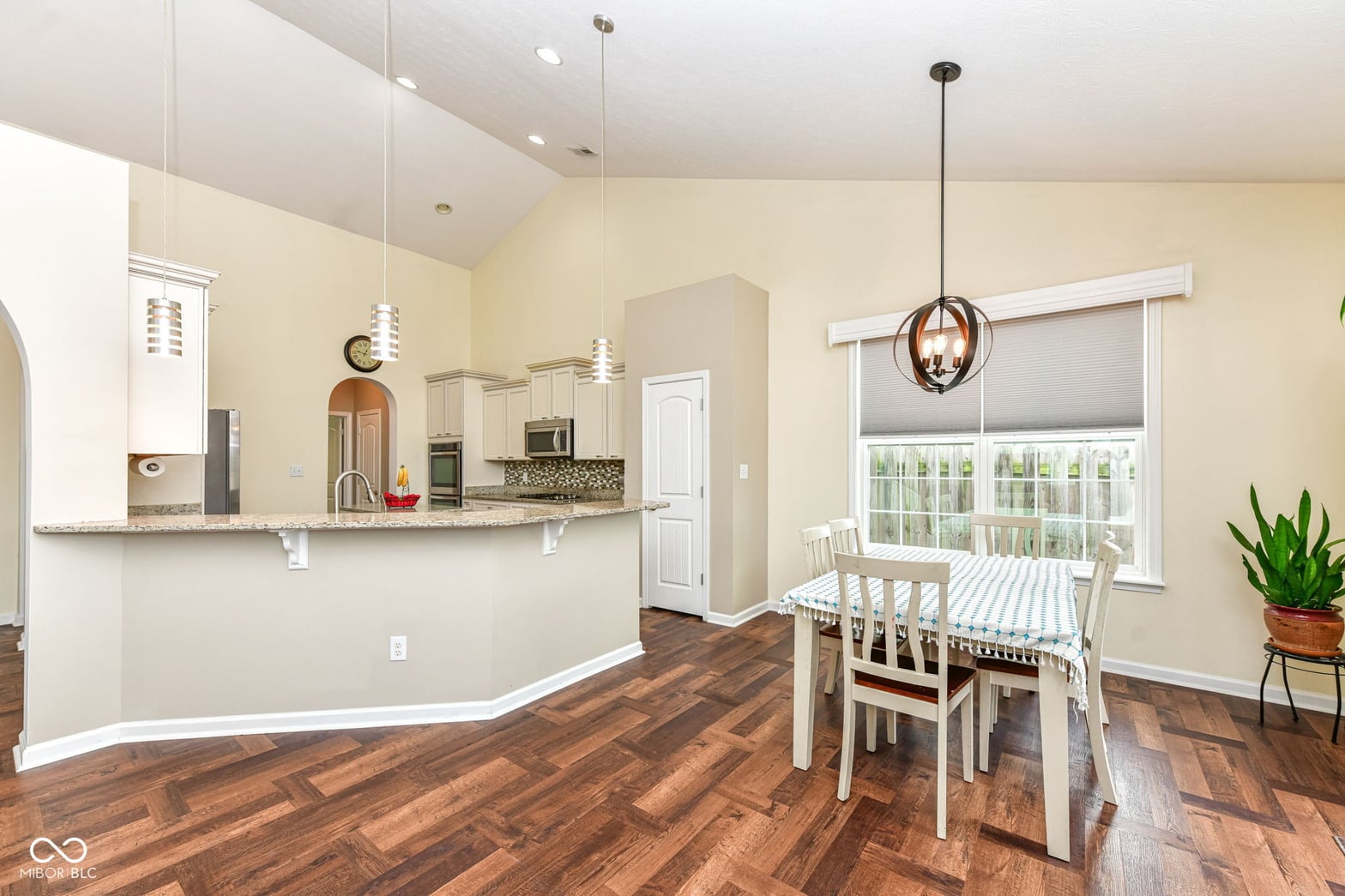 Bright open kitchen with granite counters and hardwood floors.