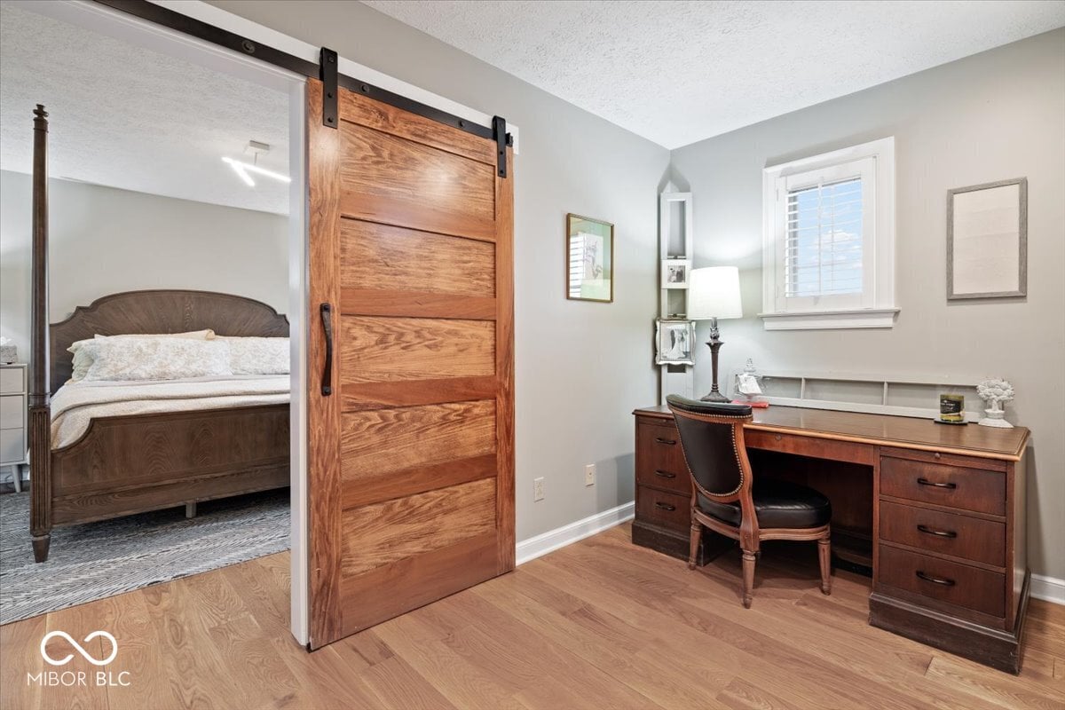Spacious primary bedroom with barn door and built-in workspace.