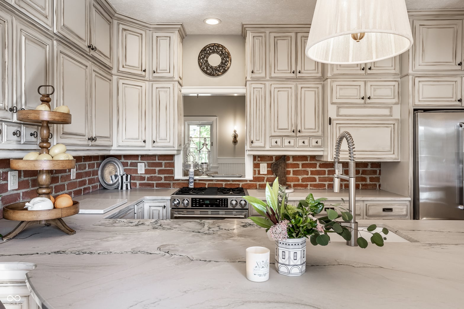 Elegant kitchen with marble island and classic brick backsplash.
