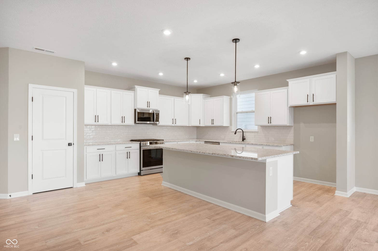 Bright modern kitchen with granite island and stainless appliances.