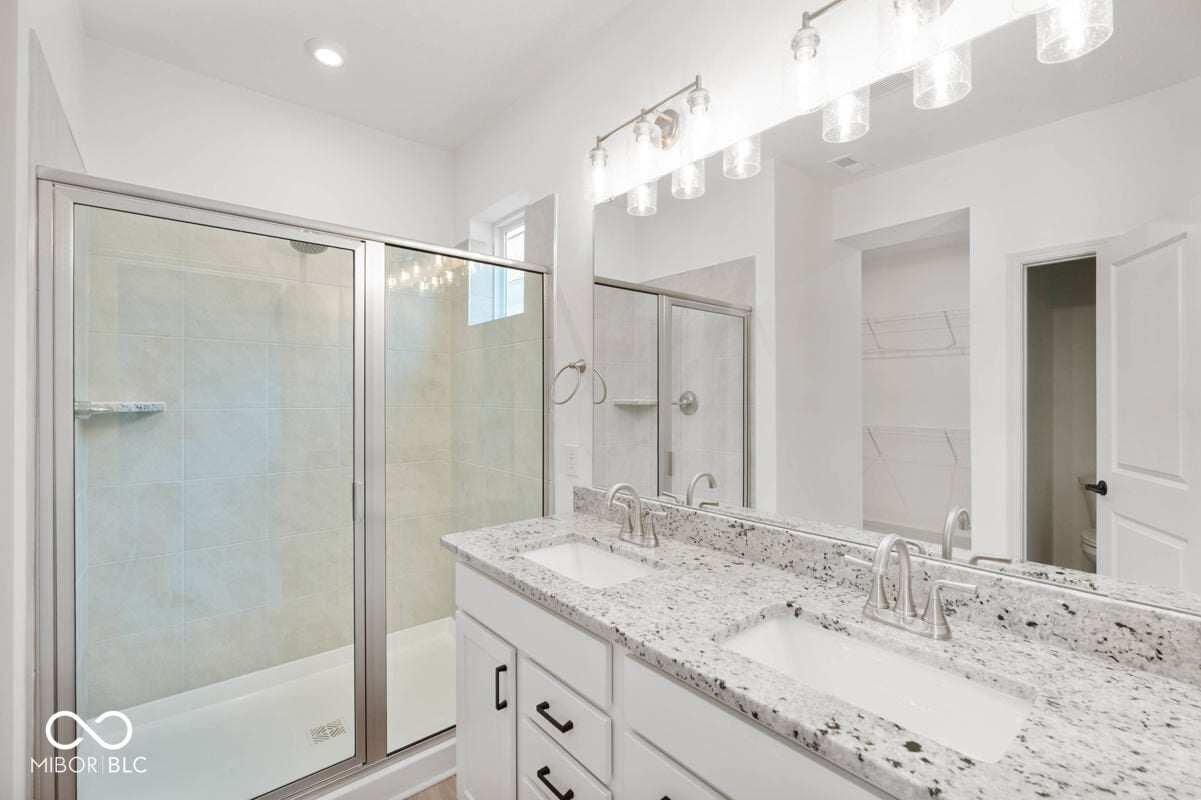 Luxurious primary bath with dual vanity and frameless shower.
