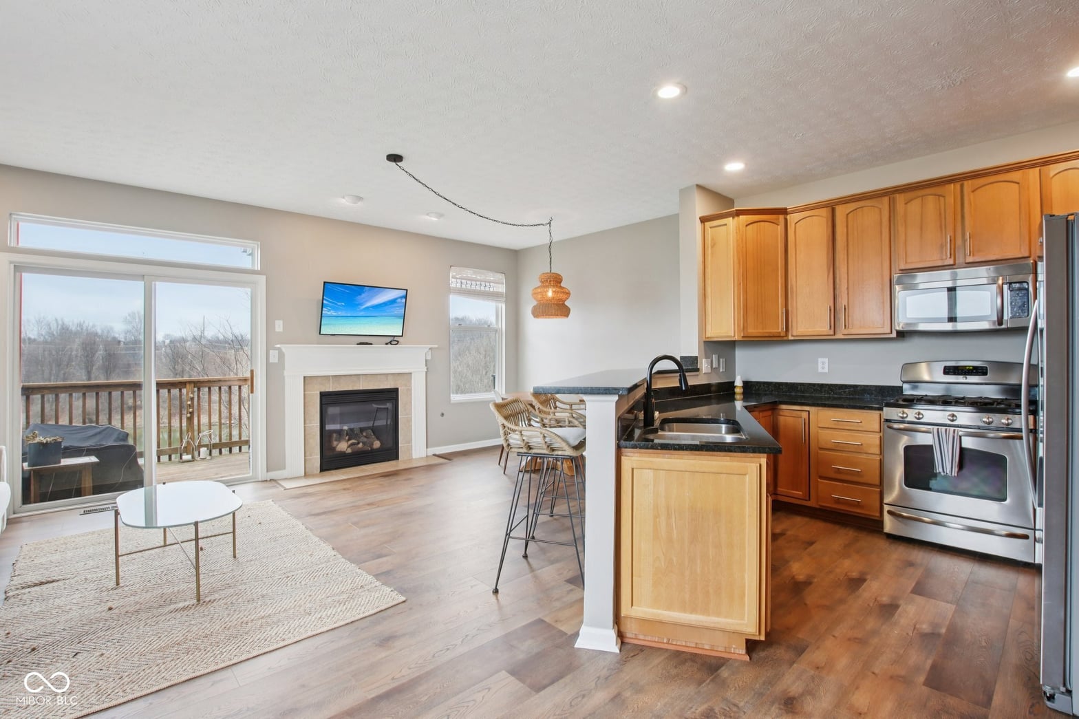 Open concept kitchen with fireplace and deck views.