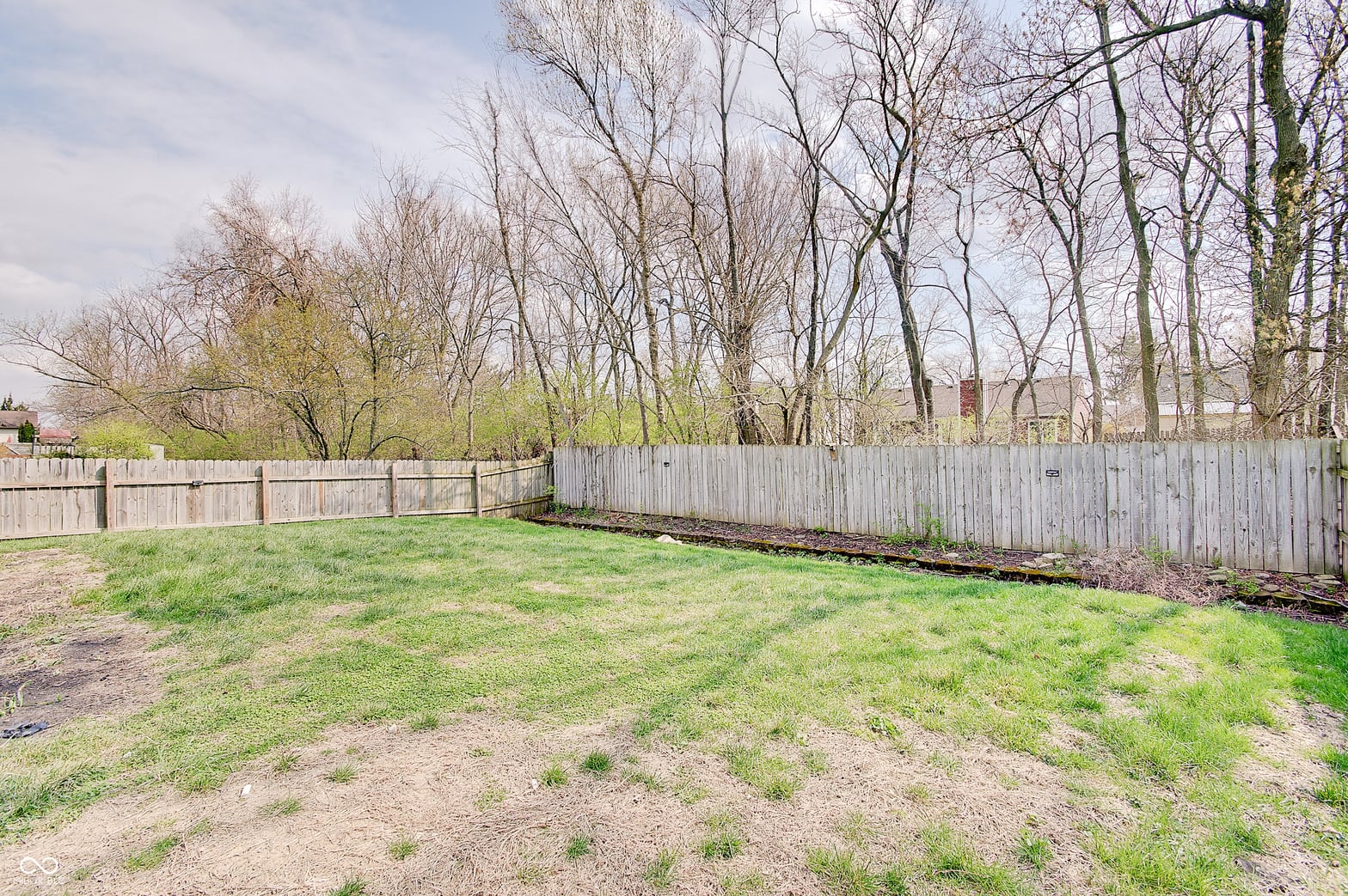 Large fenced yard with mature trees and open lawn.