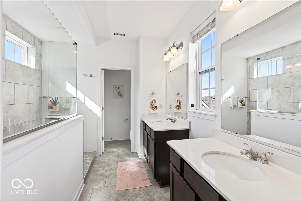 Spa-like primary bath with dual vanities and walk-in shower.
