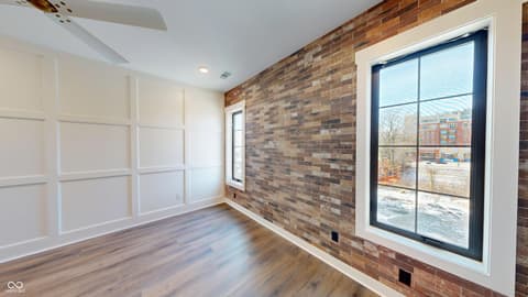 Bedroom at 717 Livingstone Drive, Carmel, IN — Modern loft bedroom with exposed brick and hardwood floors.