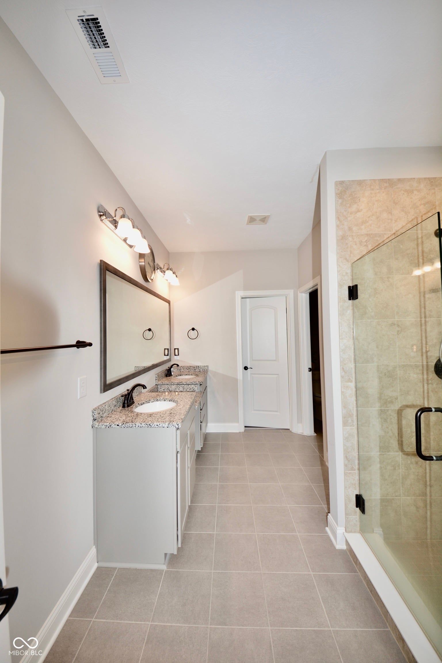 Spacious primary bath with dual vanities and frameless shower.