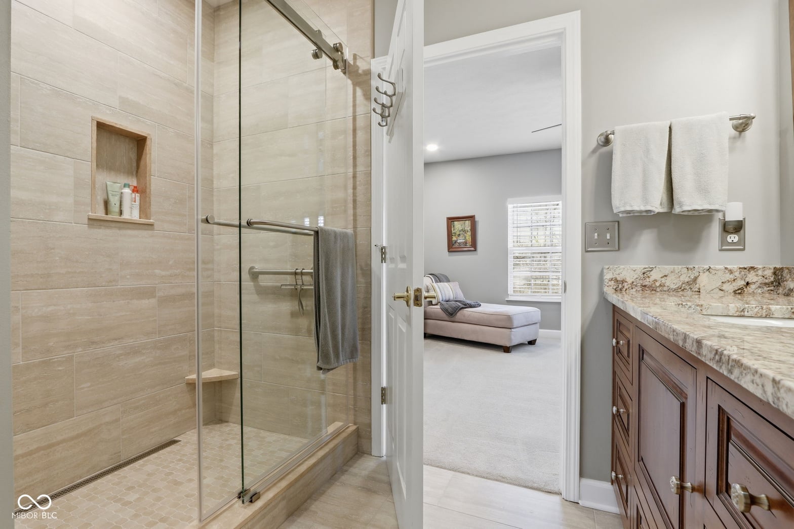 Luxurious primary bath with frameless shower and granite counters.
