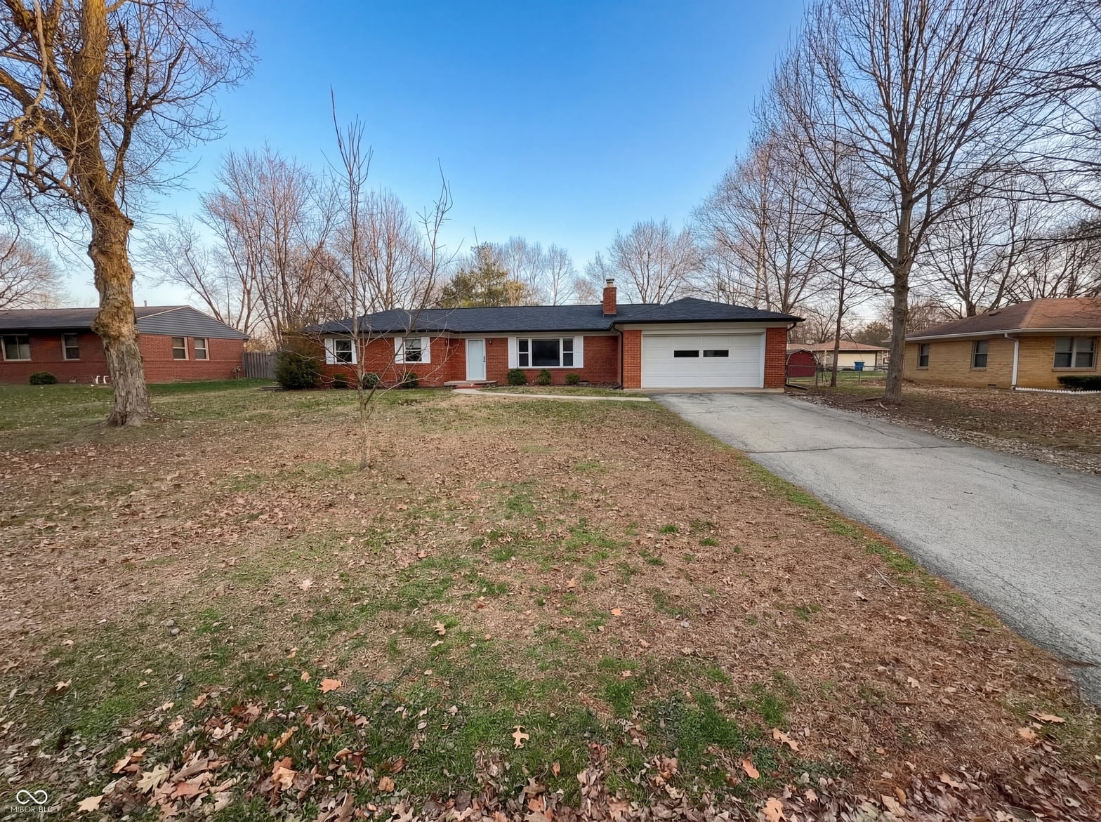 Front exterior at 10209 Broadway Street, Indianapolis, IN — Classic brick ranch on large wooded lot.
