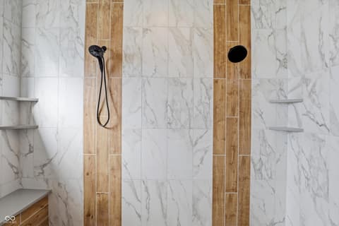 Primary bathroom at 17112 Sanders Farm Circle, Westfield, IN — Luxurious marble shower with modern wood accents.