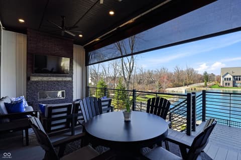 Outdoor living area at 17112 Sanders Farm Circle, Westfield, IN — Luxury waterfront covered patio with fireplace and views.