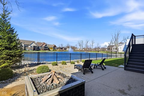 Outdoor living area at 17112 Sanders Farm Circle, Westfield, IN — Stunning waterfront patio with fire pit and lake views.