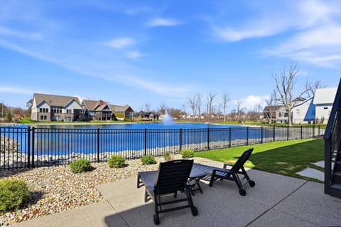 Outdoor living area at 17112 Sanders Farm Circle, Westfield, IN — Lakefront patio with water views and seating area.