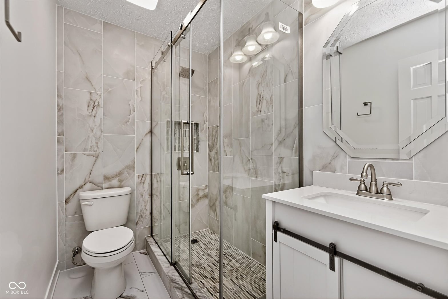 Luxurious spa-like primary bathroom with marble and frameless glass.