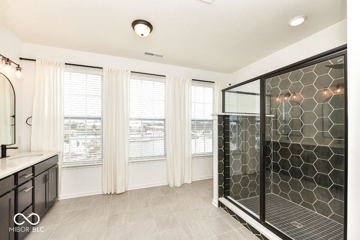Luxe primary bath with hexagonal tile shower and abundant natural light.
