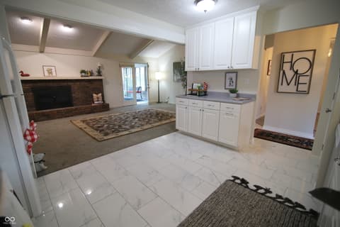 Family room at 104 Apple Tree Court, Fishers, IN — Renovated open concept with fireplace and marble floors.