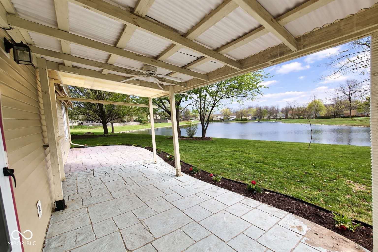 Lakefront patio with pergola and manicured grounds.