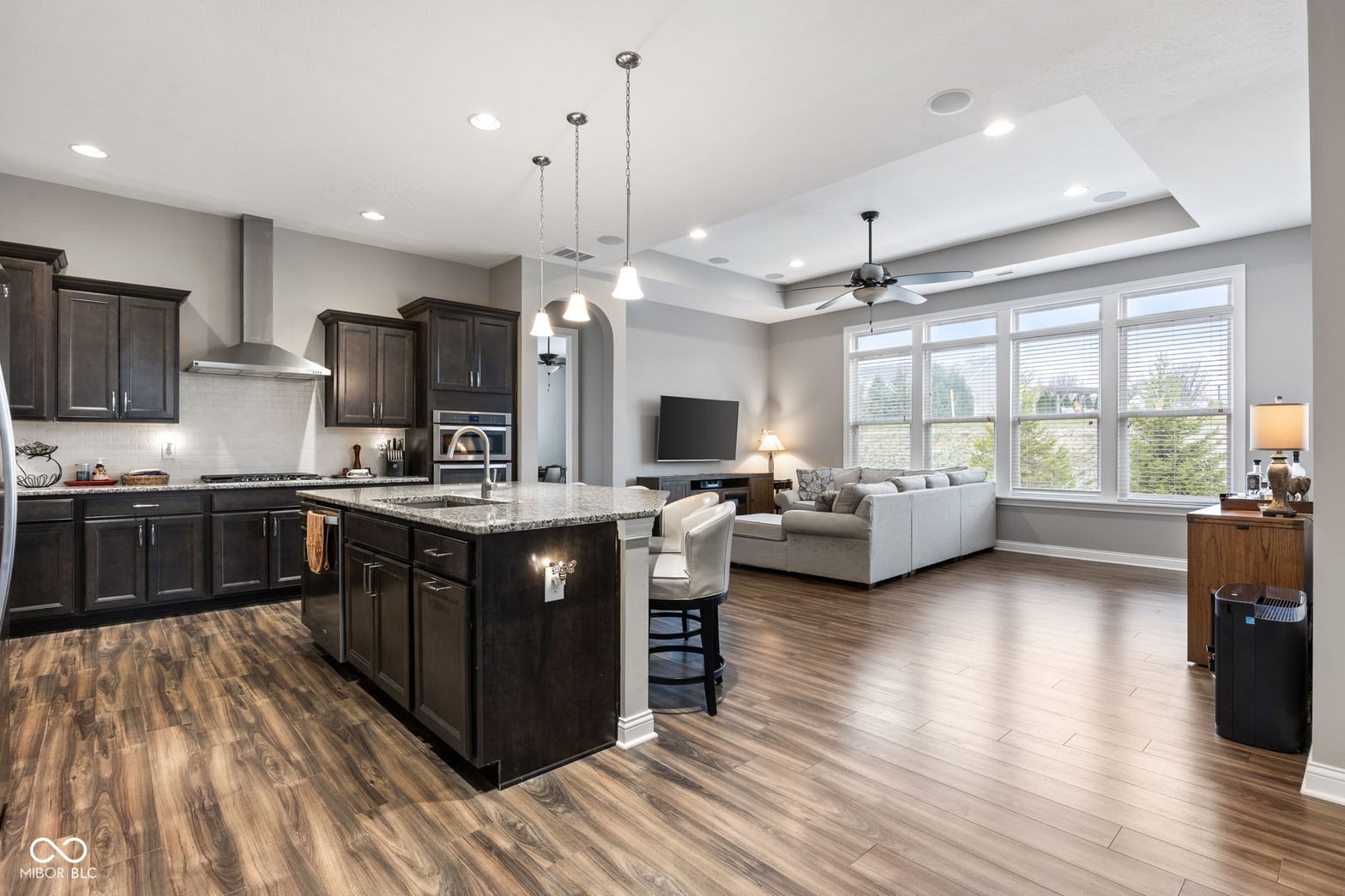 Modern kitchen with granite island opens to living space.