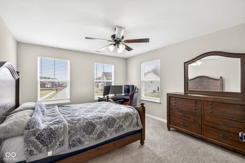 Primary bedroom at 12338 French Cattle Way, Noblesville, IN — Bright primary bedroom with multiple windows and workspace.