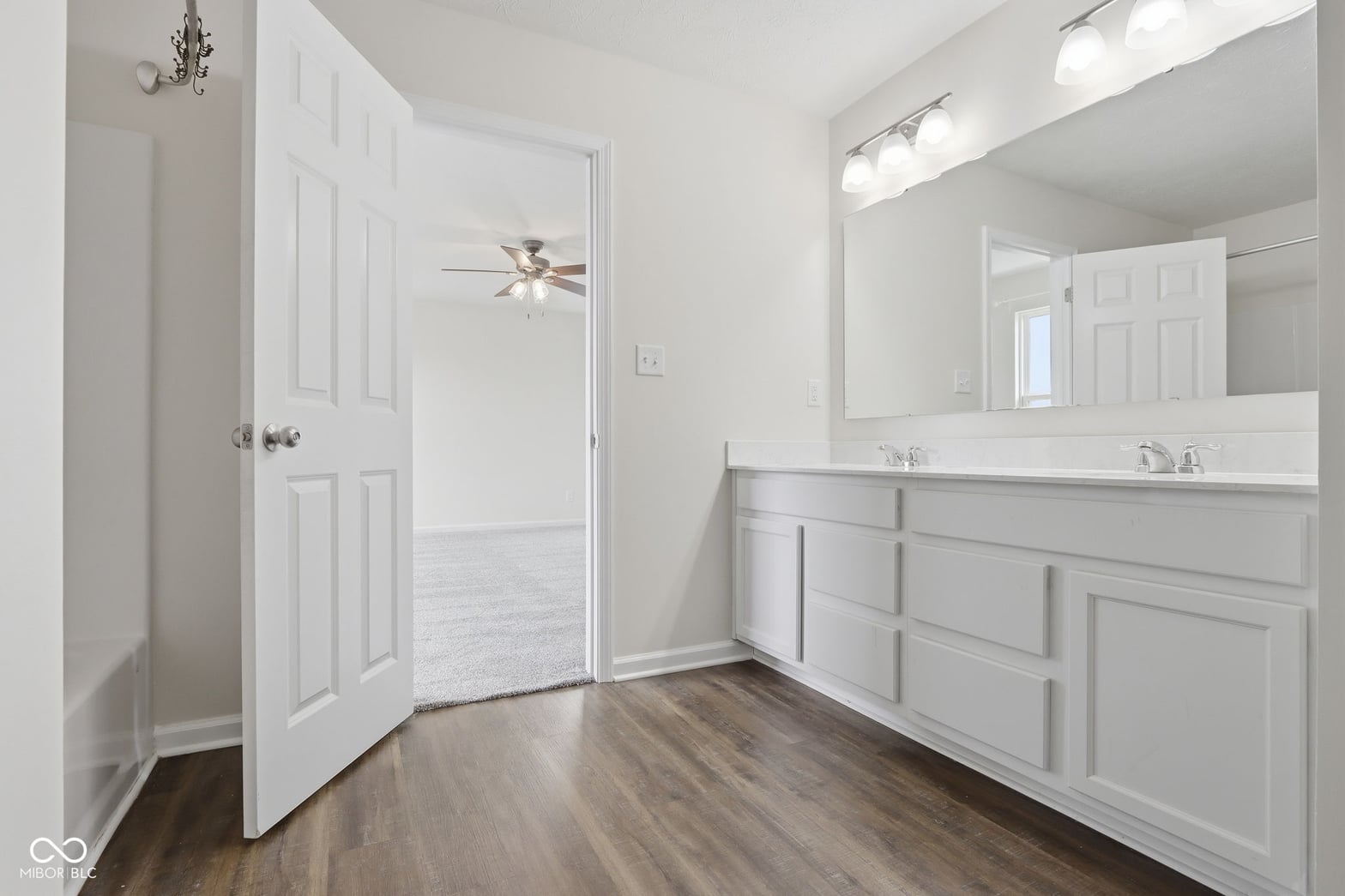 Spacious primary bath with double vanity and hardwood floors.