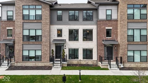 Front exterior at 11571 Huffington Street, Carmel, IN — Modern townhome with sleek brick and stone exterior.