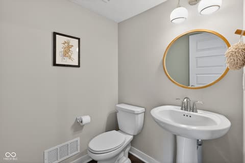 Bathroom at 11571 Huffington Street, Carmel, IN — Bright, modern powder room with stylish gold-framed mirror.