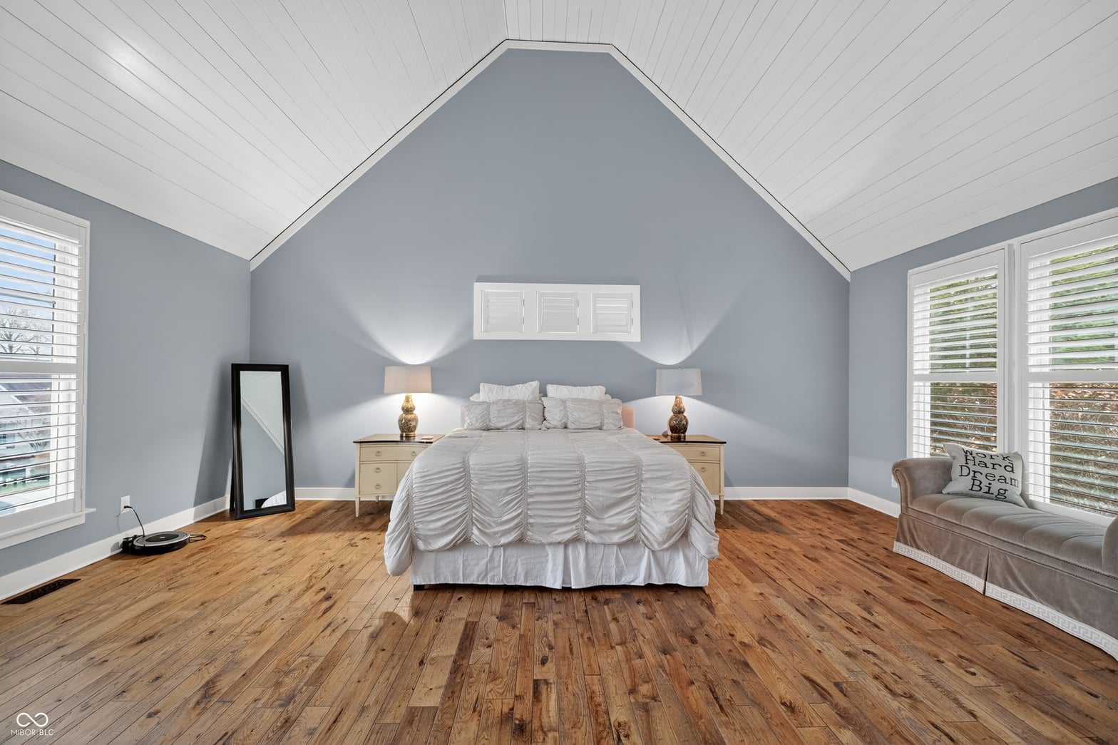 Spacious primary suite with vaulted ceilings and shutters.