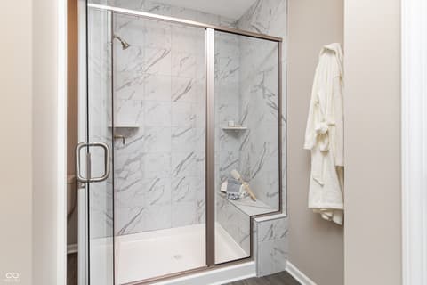 Primary bathroom at 7591 Catfish Drive, Noblesville, IN — Luxurious marble shower with built-in bench seating.