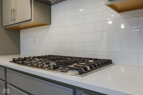 Kitchen at 18808 Cromarty Circle, Noblesville, IN — Modern kitchen with gas cooktop and floating brass shelves.