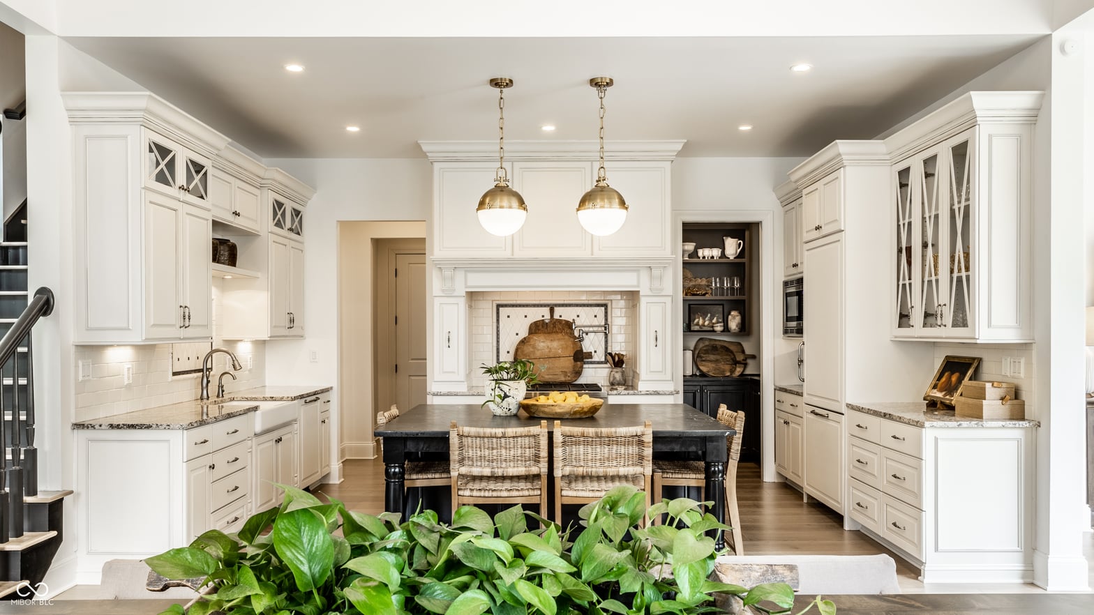 Elegant white kitchen with large island and fireplace.