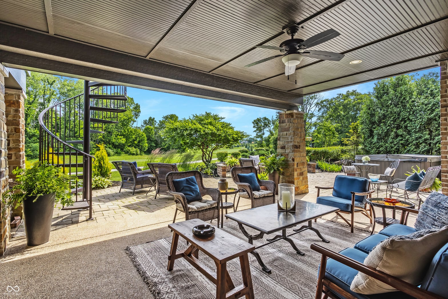 Luxurious covered patio with spiral stairs and fireplace.