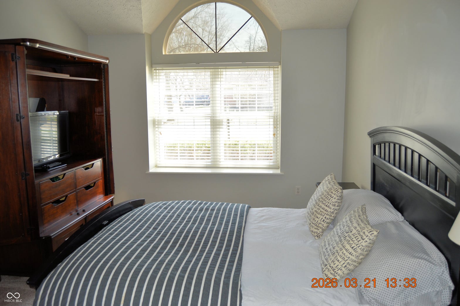 Bright bedroom with elegant arched window and natural light.