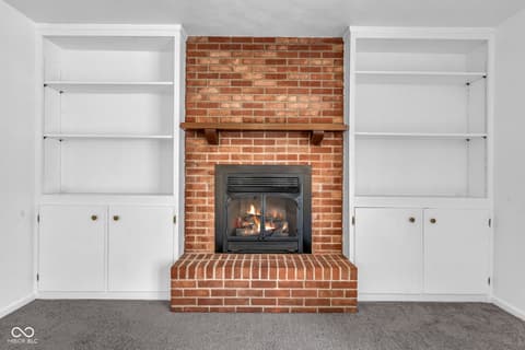 Living room at 18 Wilson Drive, Carmel, IN — Charming fireplace with built-in shelving and brick accent.