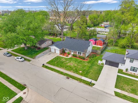 Aerial view at 18 Wilson Drive, Carmel, IN — Charming brick ranch on tree-lined suburban lot with garage.