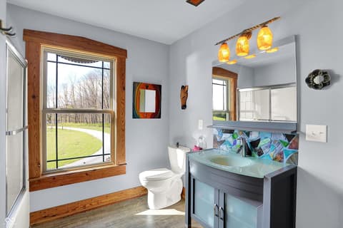 Primary bathroom at 25811 State Road 19, Arcadia, IN — Bright renovated bath with artistic tile and pendant lights.