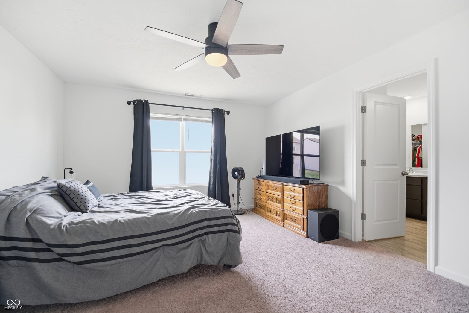 Bright primary bedroom with large windows and modern amenities.