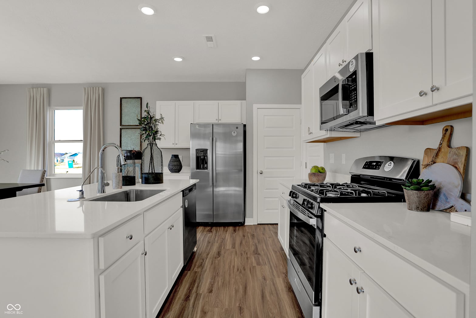 Modern white kitchen with stainless steel appliances.