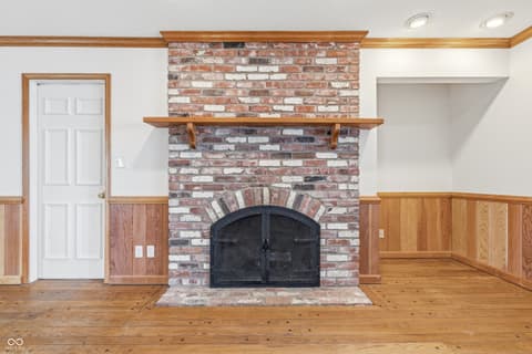 Family room at 15 Wildwood Drive, Carmel, IN — Charming brick fireplace focal point with wood details.