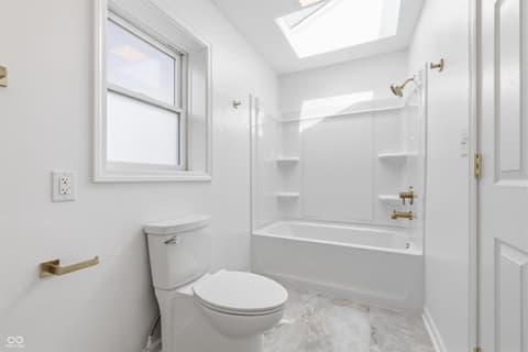 Bathroom at 15 Wildwood Drive, Carmel, IN — Bright, modern bathroom with skylight and marble floors.