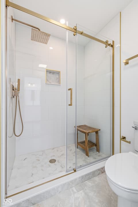 Primary bathroom at 15 Wildwood Drive, Carmel, IN — Luxury spa-inspired shower with marble and brass finishes.