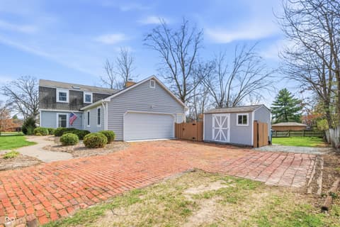 Front exterior at 15 Wildwood Drive, Carmel, IN — Charming colonial with brick driveway and storage shed.