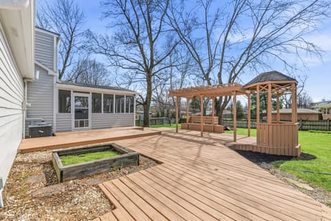 Outdoor living area at 15 Wildwood Drive, Carmel, IN — Spacious composite deck with pergola and garden beds.