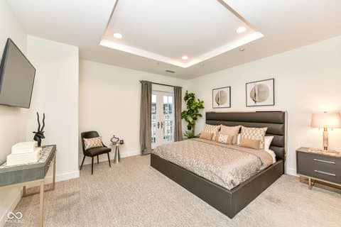 Primary bedroom at 30 W Main Street, Carmel, IN — Spacious primary suite with tray ceiling and city views.