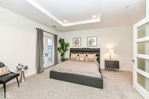 Primary bedroom at 30 W Main Street, Carmel, IN — Spacious primary suite with tray ceiling and balcony access.