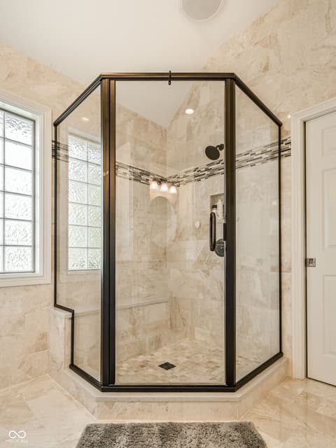 Primary bathroom at 12344 St Armands Circle, Carmel, IN — Luxurious walk-in shower with elegant travertine tiling.